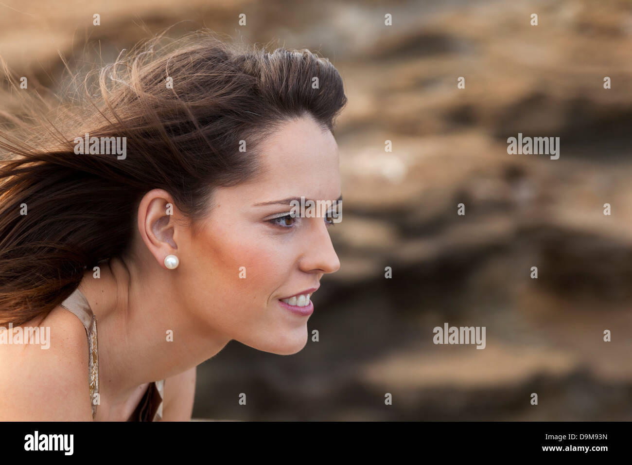 Hübsche junge Frau mit dem Wind ihr Haar wegsehen Lächeln auf den Lippen, Stockfoto