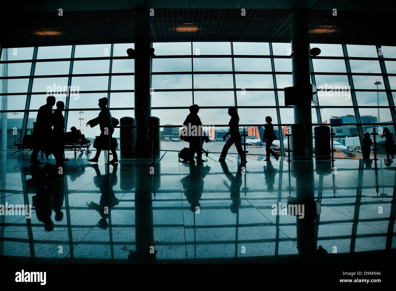 Silhouetten von Personen mit Gepäck zu Fuß am Flughafen Stockfoto