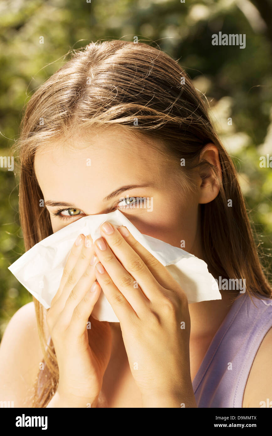 Junge Frau mit Allergie an sonnigen Tag ist ihre Nase abwischen. Stockfoto