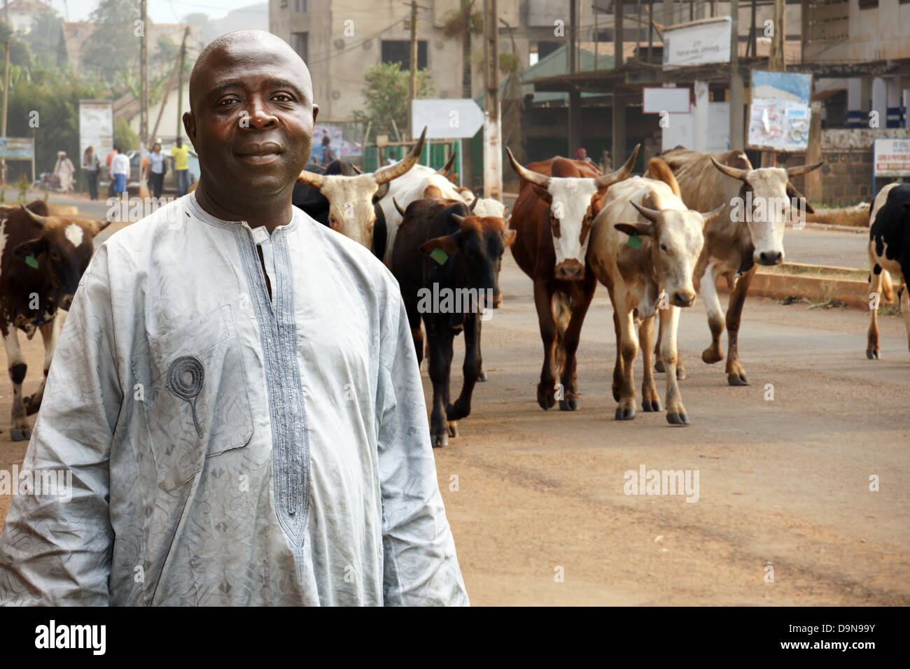 Afrikanische Rinder Bauern oder Hirten seiner Herde Kühe auf einer belebten Straße führt Stockfoto