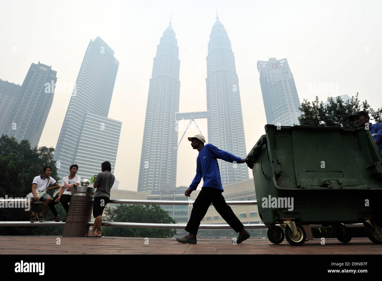 23. Juni 2013 - Kuala Lumpur, Malaysia - A Arbeiter zieht einen Müll-Wagen wie Dunst Malaysias ikonischen Petronas Twin Towers (C) in Kuala Lumpur erstreckt. Malaysia erklärte einen Ausnahmezustand in einigen Bereichen nach Verunreinigung der Luft durch illegale Brennen von Wäldern und Torf landet in Indonesien gefährliche Ausmaße. (Kredit-Bild: © Najjua Zulkefli/ZUMAPRESS.com) Stockfoto