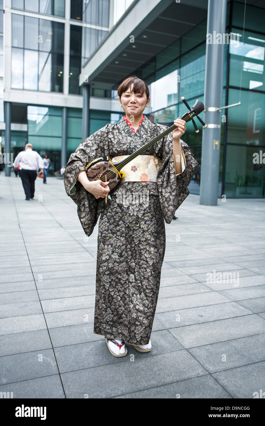 Sanshin - drei stringed traditionelles Musikinstrument aus Okinawa angezeigt wird von einem japanischen Frauen tragen einen Kimono-Bademantel Stockfoto