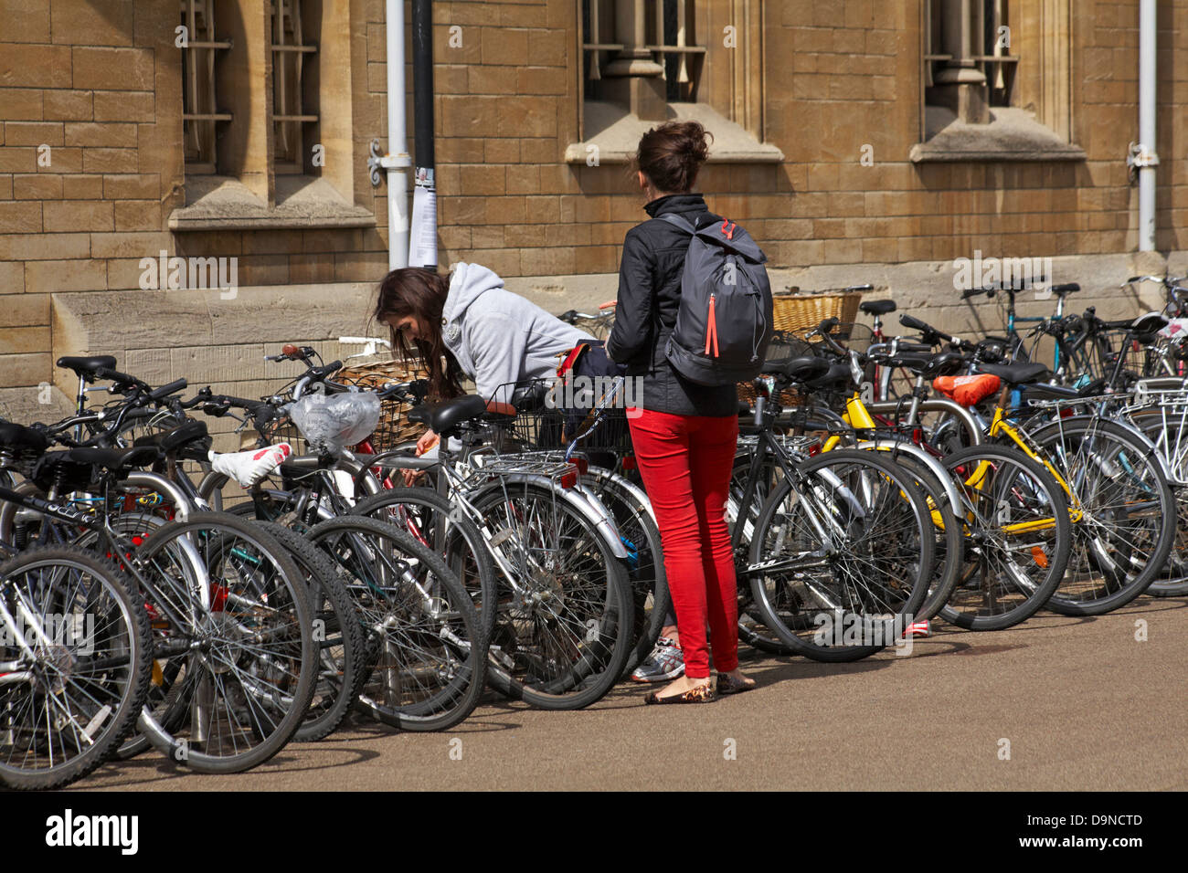 Zwei junge Frauen, eine davon mit Reihen von Fahrrädern in Oxford, Oxfordshire, Großbritannien, im Mai Stockfoto