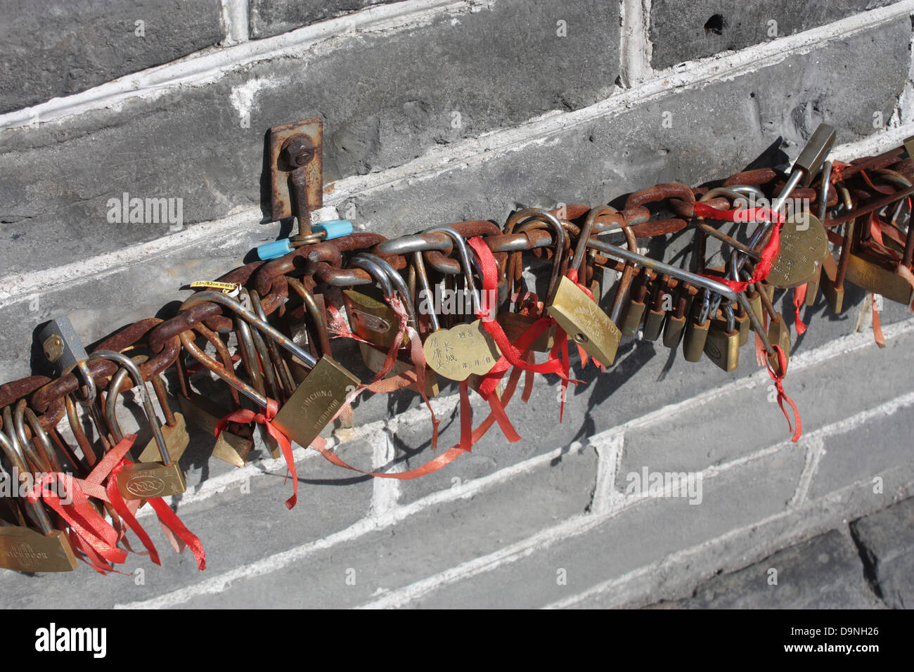 Schlüssel und Schlösser verkettet und an die Große Mauer in China zusammen mit roten Bändern vertreten, Glücksbringer und Symbolik. Stockfoto