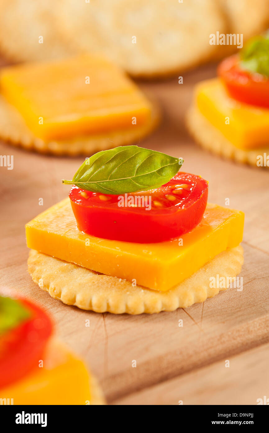 Chedder Käse und Cracker Vorspeise mit Tomaten und Basilikum Stockfoto
