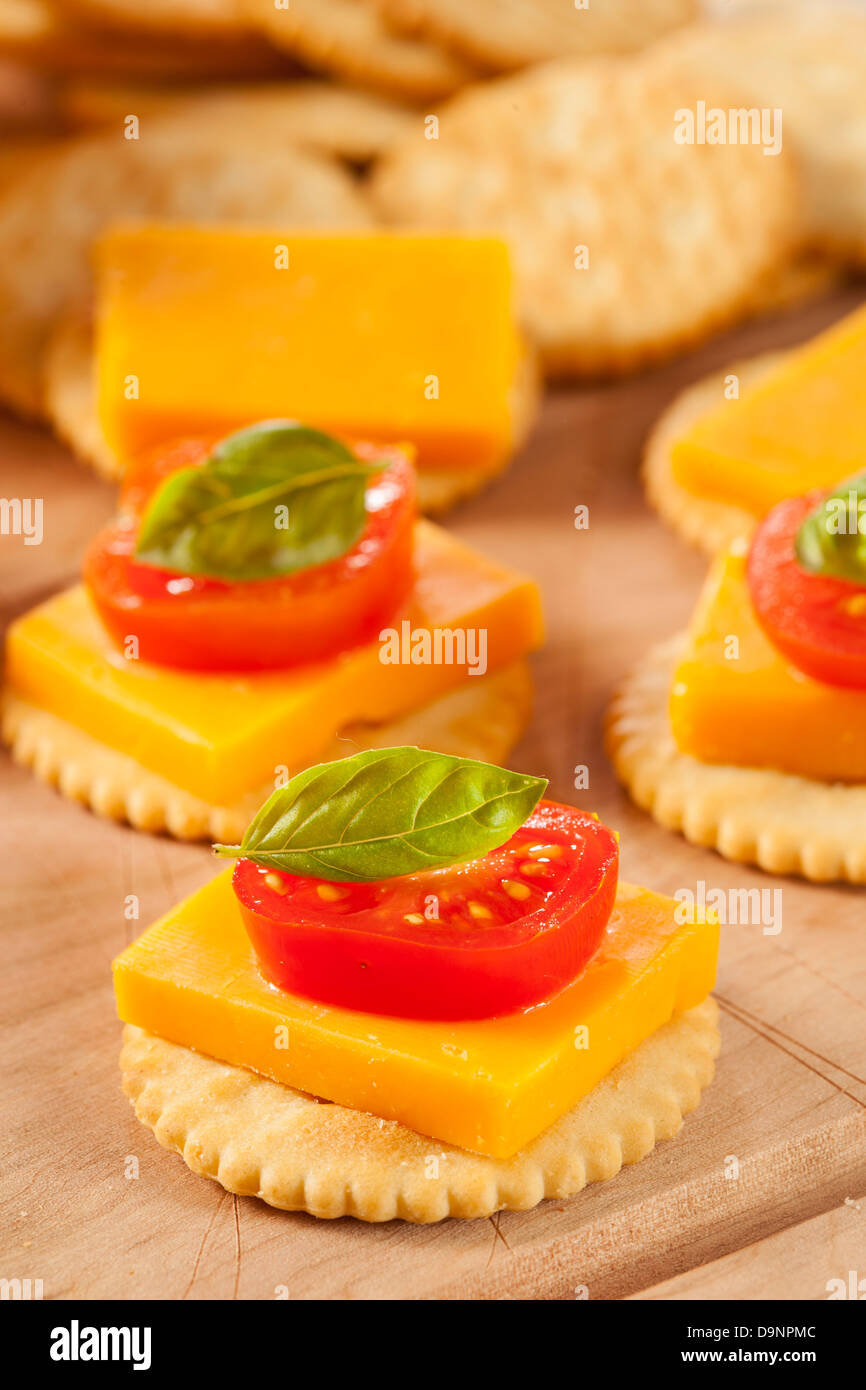 Chedder Käse und Cracker Vorspeise mit Tomaten und Basilikum Stockfoto