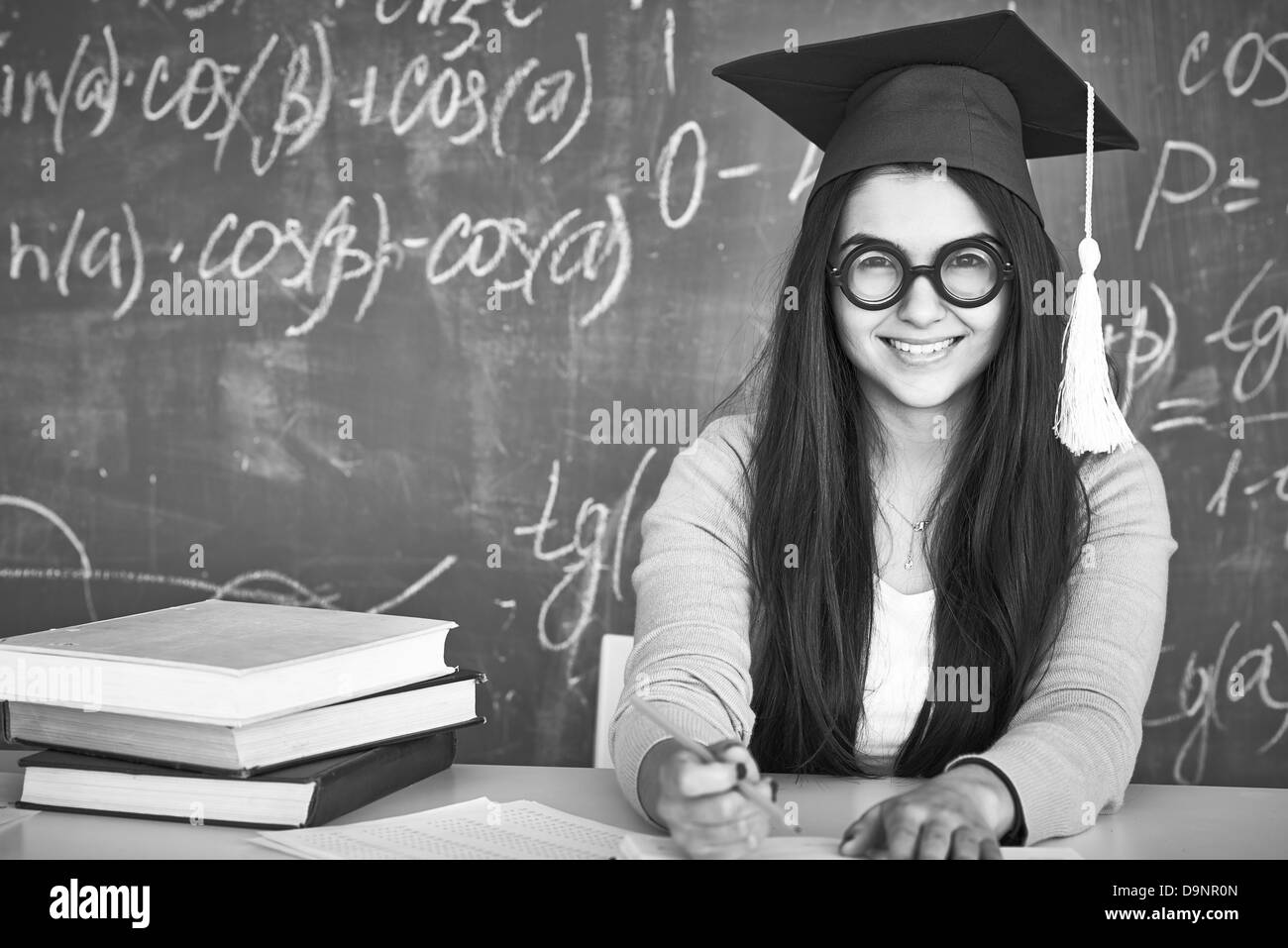 Schwarz-weiß-Bild der Schüler im Abitur Hut und Brille Blick in die Kamera auf Grund der Tafel Stockfoto
