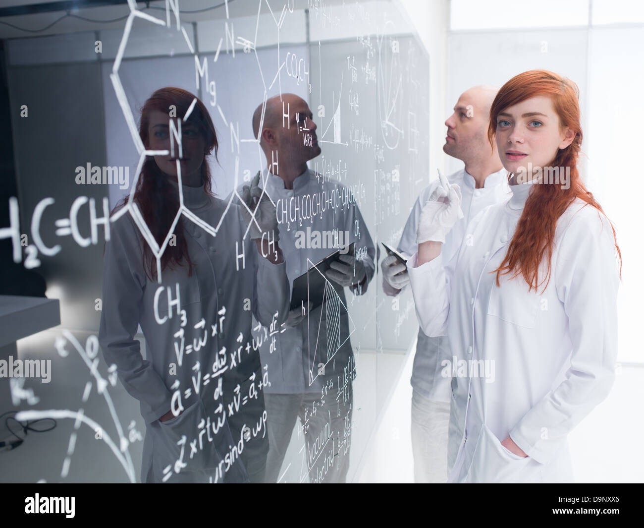 Seitenansicht eines Lehrers in einem Chemielabor analysieren Formeln von einem Schüler suchen glücklich in die Kamera auf einer Tafel geschrieben Stockfoto
