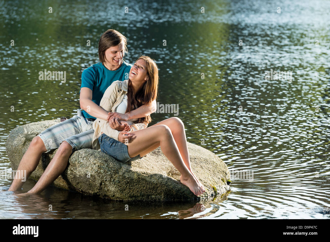 Paar in Liebe sitzt auf einem Felsen am See Stockfoto