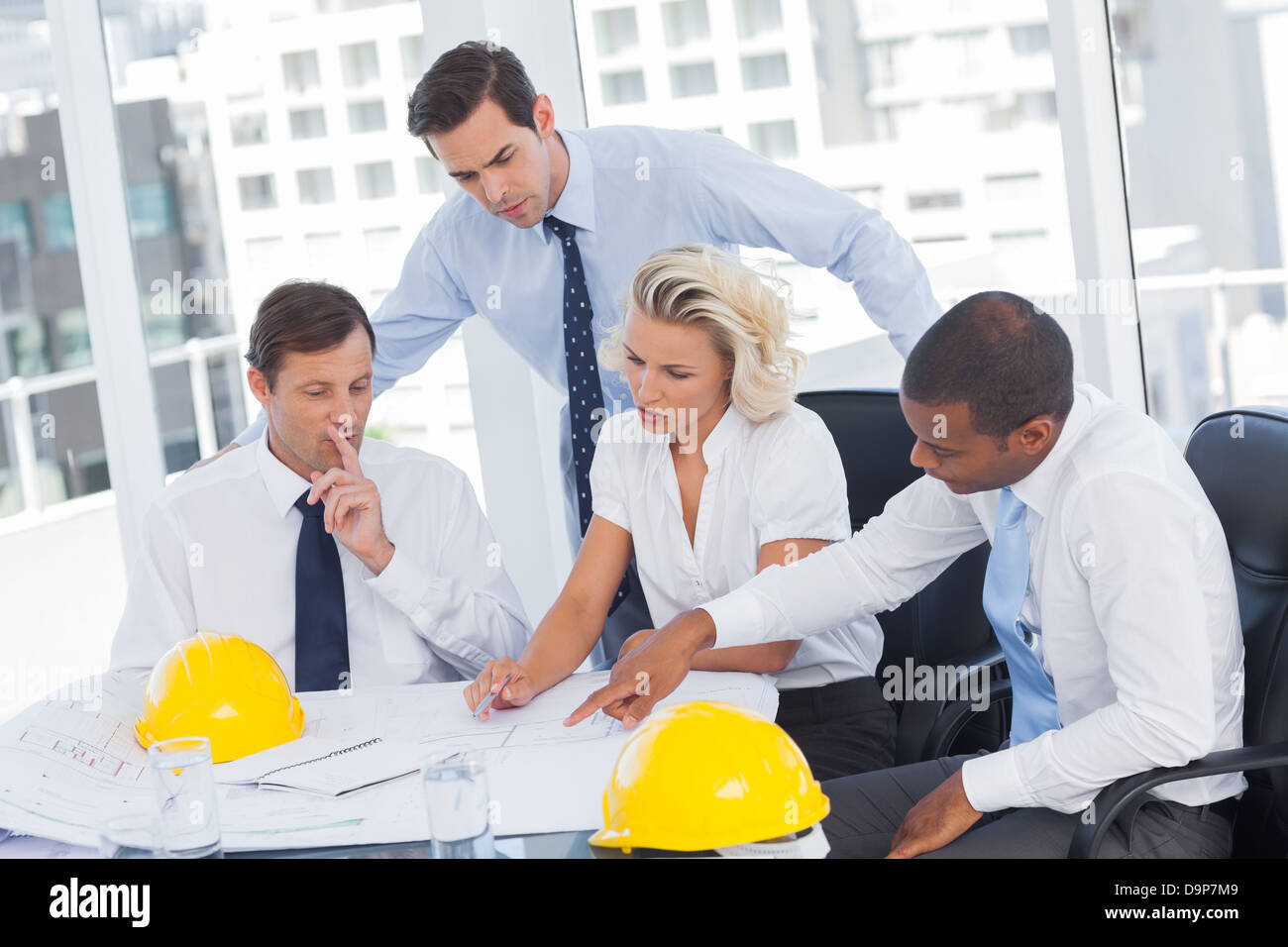 Vier Architekten arbeiten auf Blaupausen Stockfoto