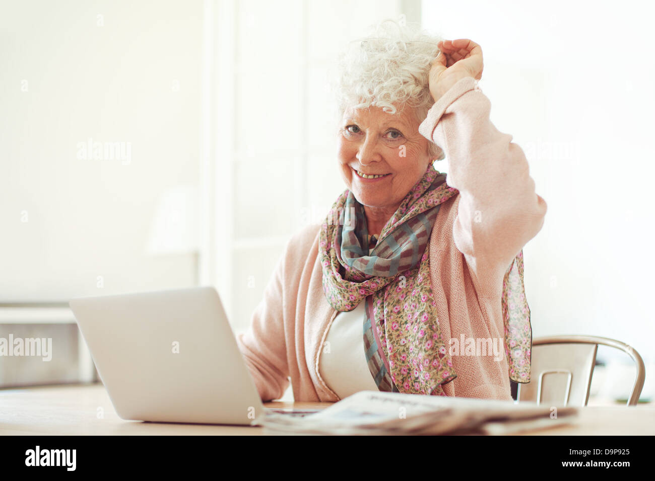 Fröhliche Großmutter zu Hause sitzen verwenden ihr laptop Stockfoto