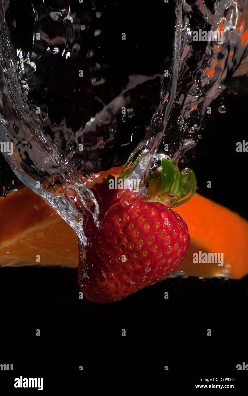 Erdbeere und orange Spritzwasser auf schwarzem Hintergrund Stockfoto