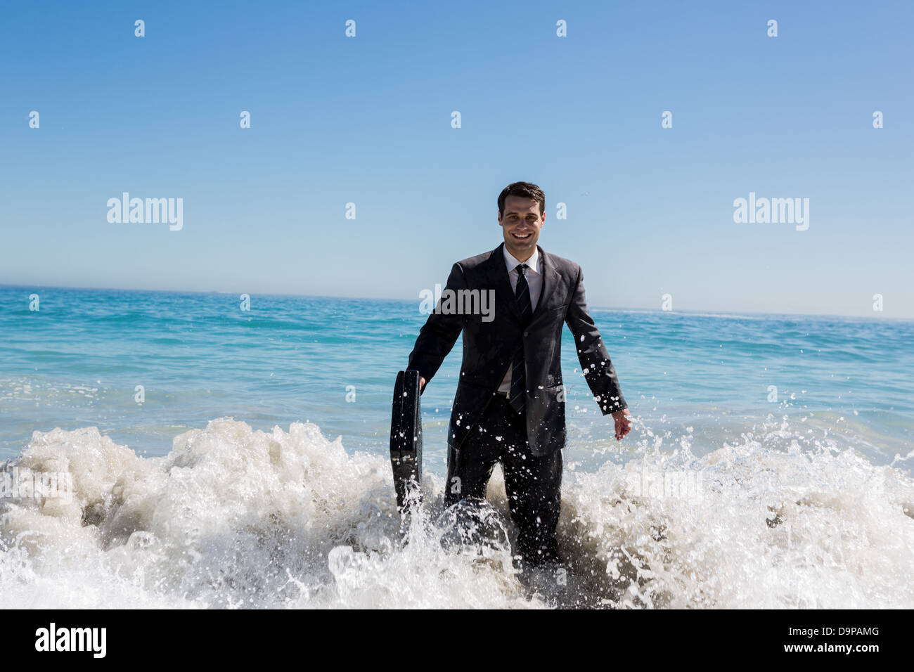 Fröhliche Geschäftsmann zu Fuß in das Meer Stockfoto