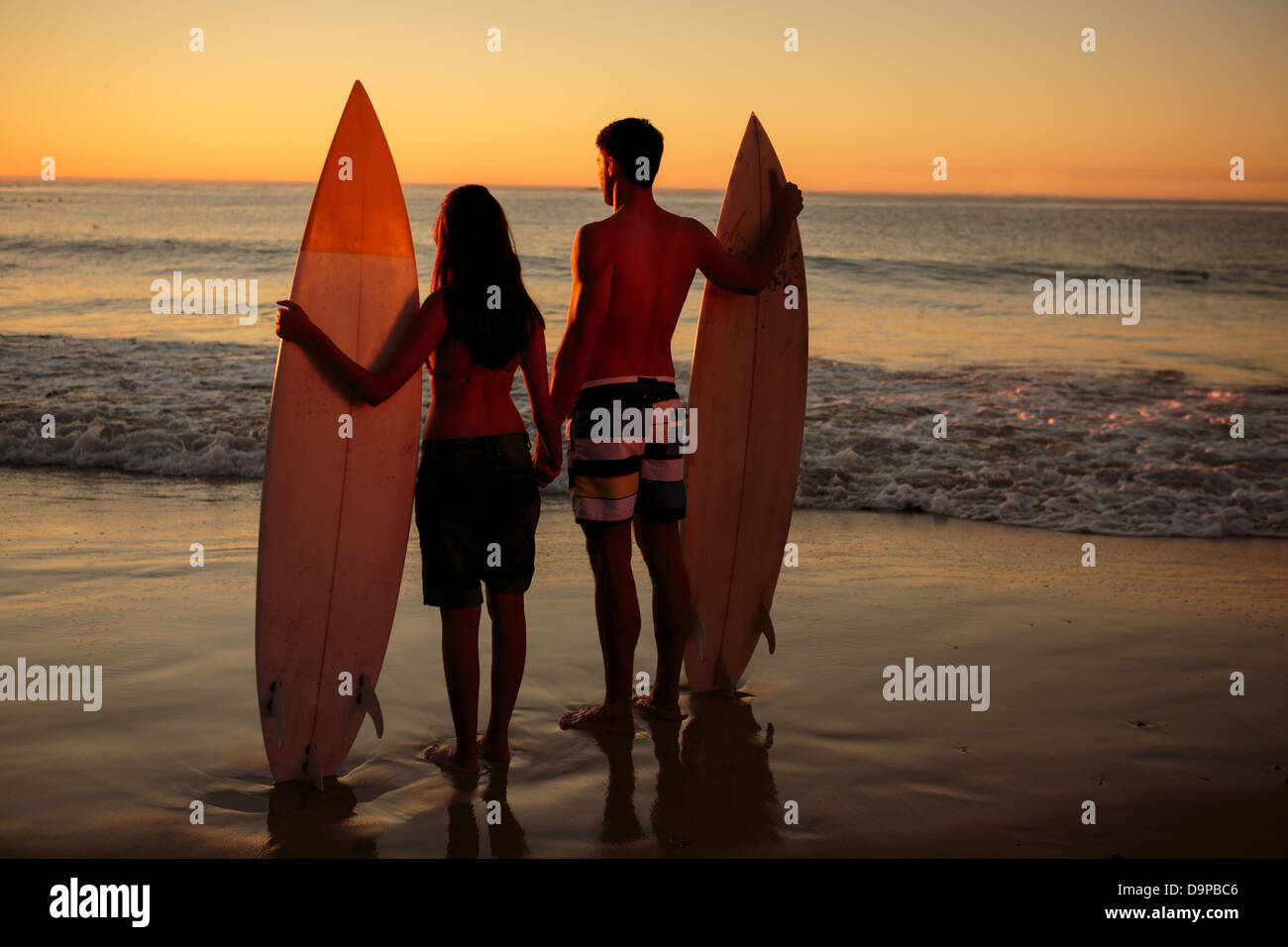 Paar Hand in hand mit Surfbretter am Strand Stockfoto
