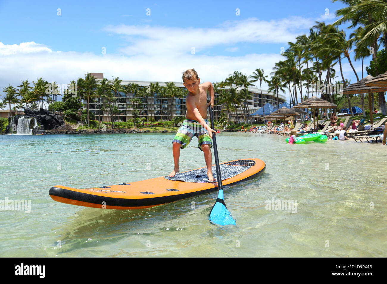 Boy am Paddel Board im Resort in Hawaii, USA Stockfoto