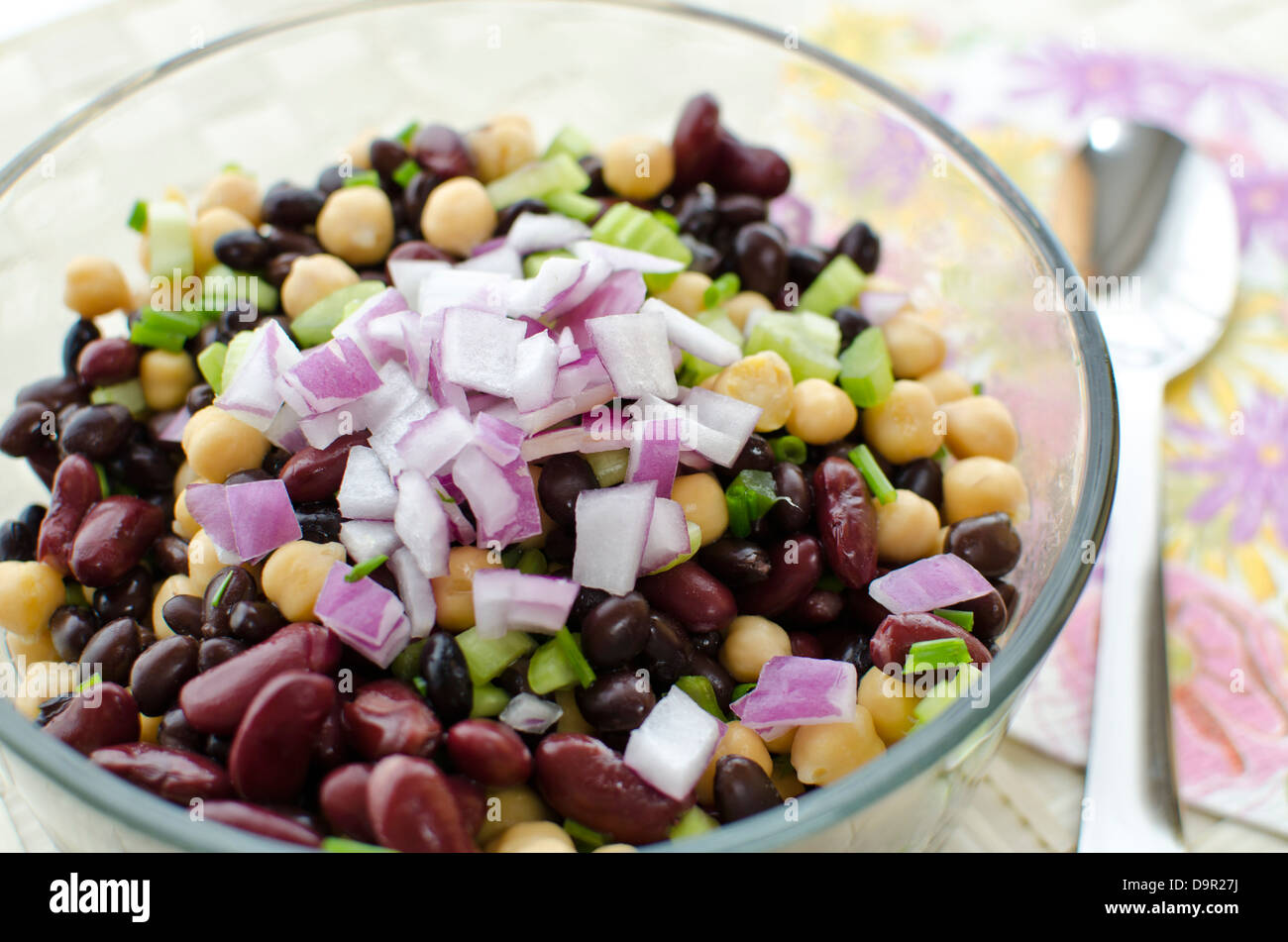 Schüssel mit Bohnen-Salat mit Kichererbsen, schwarzen Bohnen und Kidney-Bohnen frisch zubereitet. Garniert mit gehackten roten Zwiebeln. Stockfoto