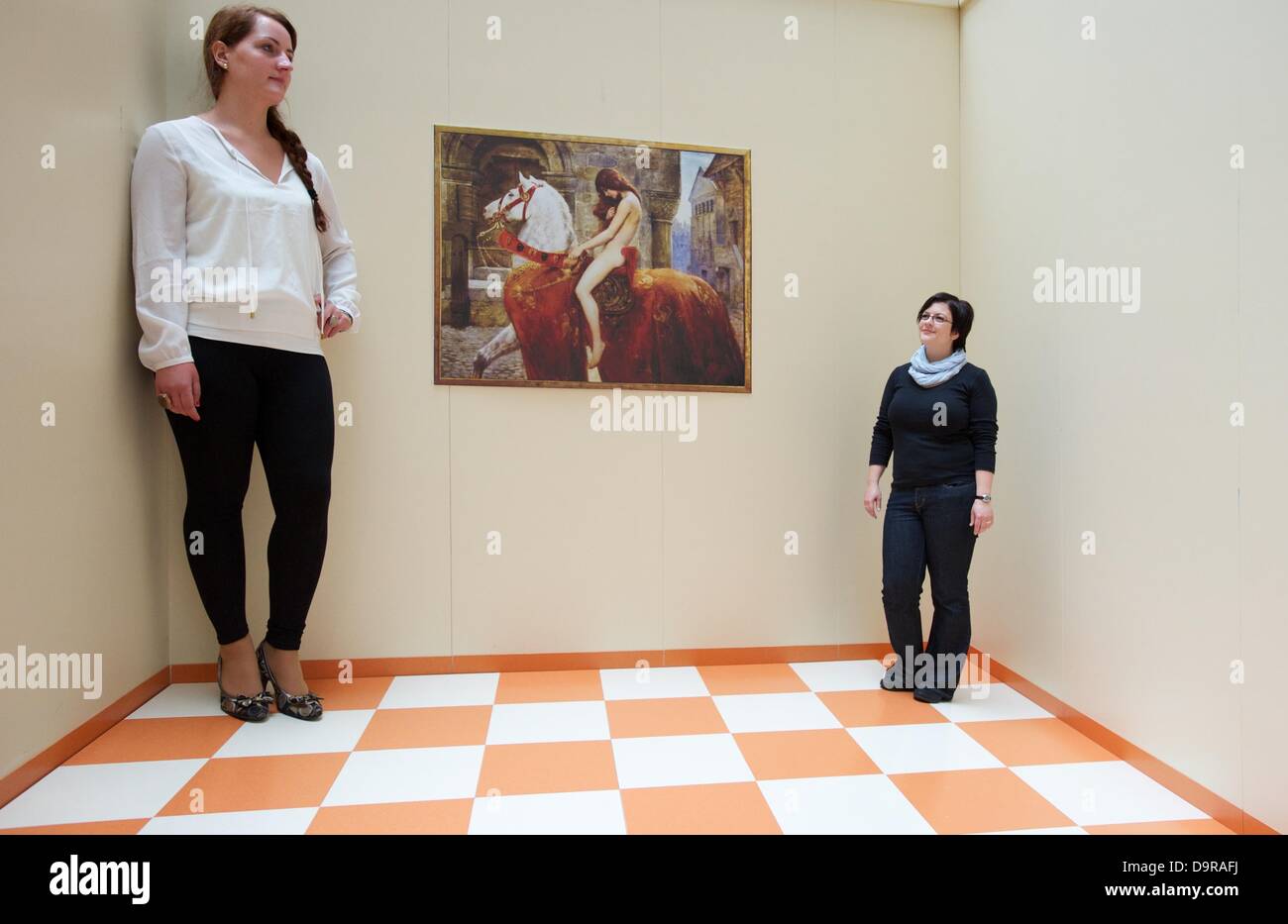 Zwei Frauen stehen in einem Ames-Raum, wo die Proportionen so Manipultated sind, dass eine Frau so wie ein Riese in der Ausstellung "Streifzug:Der:Sinne" in Leipzig, Deutschland, 25. Juni 2013. Die Ausstellung zeigt Techniken der optische Täuschung in der Staedtisches Kaufhaus in Leipzig vom 25 Juni bis 7. Juli 2013. Foto: PETER ENDIG Stockfoto