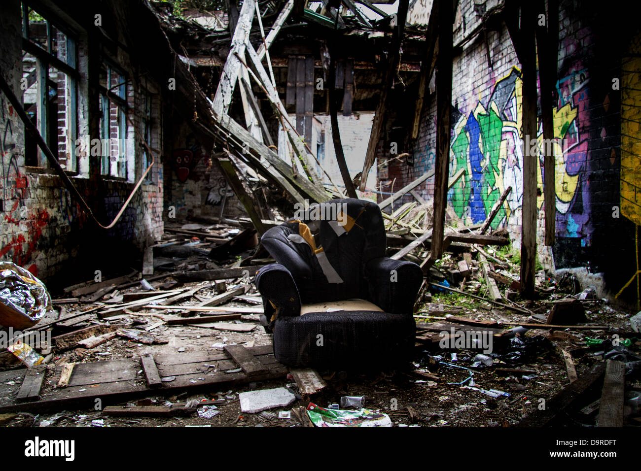 Riss-Höhle, einen alten Sessel sitzt in der Mitte einer einstürzenden Gebäude umgeben von Nadeln und anderen Drogen-Utensilien Stockfoto