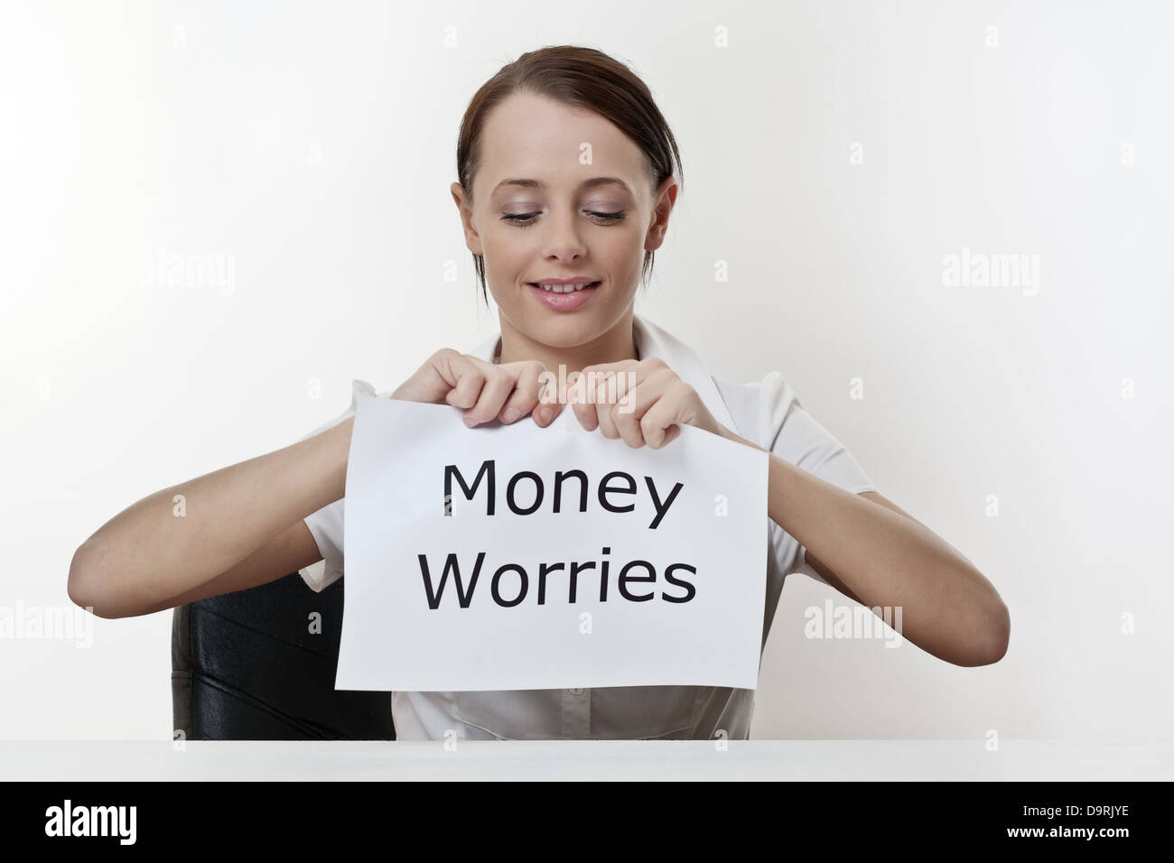 Frau sitzt an einem Schreibtisch rund um ihre Geldsorgen loszuwerden Stockfoto