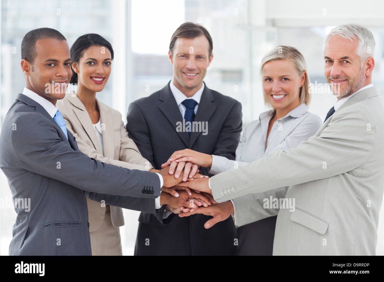 Gruppe des Lächelns Geschäftsleute häufen sich ihre Hände zusammen Stockfoto
