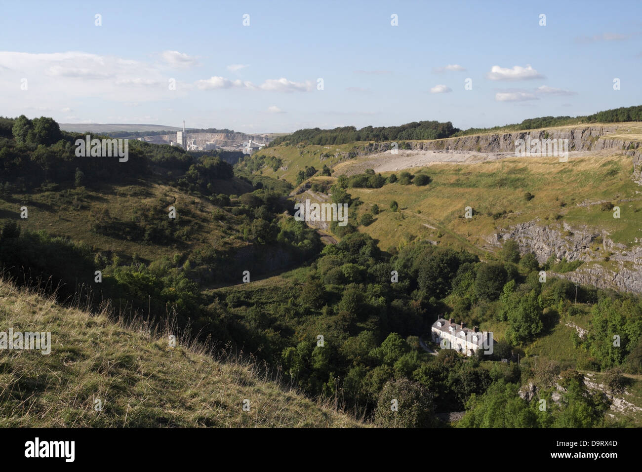 Mit Blick in das Wye Valley in Derbyshire England, auf den Blackwell Mill Cottages, arbeitet Tunstead Kalkstein in der Ferne Stockfoto