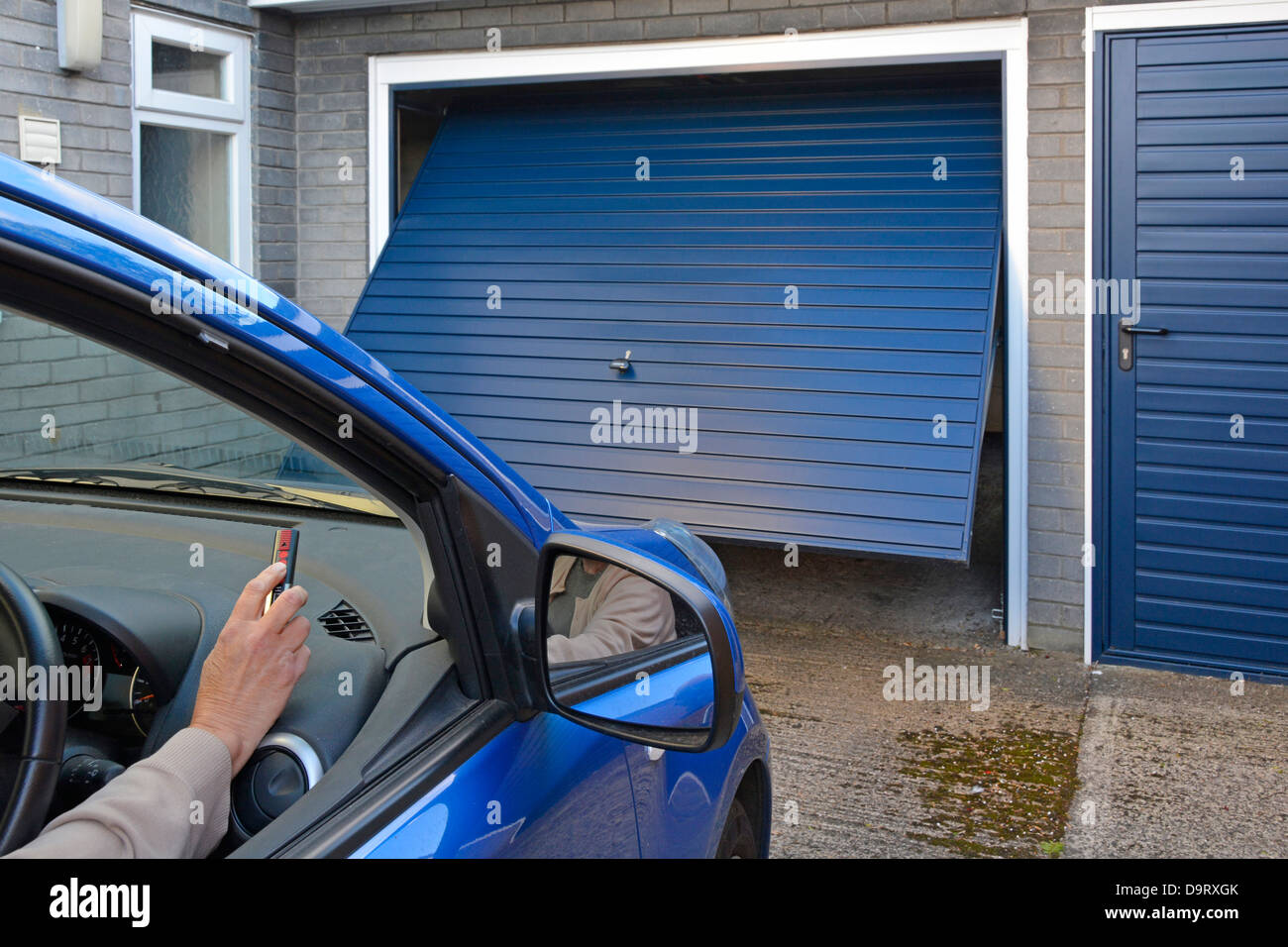 Autofahrerin Nahaufnahme mit einer Henderson-Fernbedienung, um ein Haus über dem Stahlgaragentor Essex England UK zu öffnen oder zu schließen Stockfoto