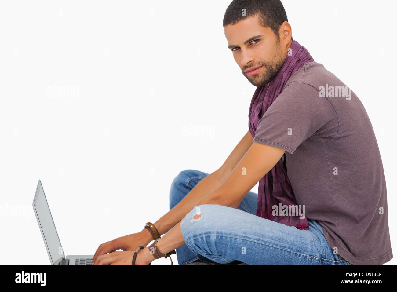 Ernster Mann trägt Schal am Boden mit laptop Stockfoto