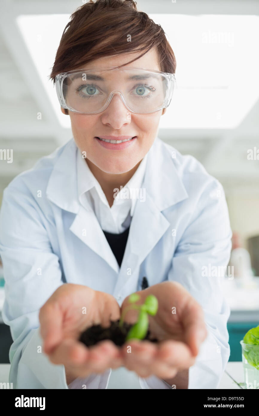 Lächelnde Frau mit winzigen Pflanze Stockfoto