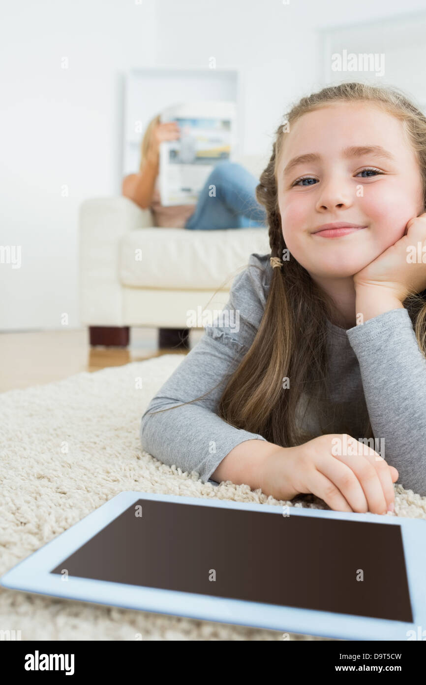 Glückliches Mädchen mit ihrem TabletPC und ihrer Mutter lesen Zeitung Stockfoto