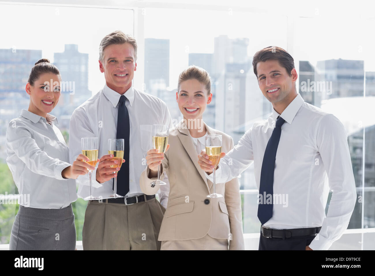 Lächelnd Team von Geschäftsleuten zu Ehren einen Erfolg mit Champagner Stockfoto