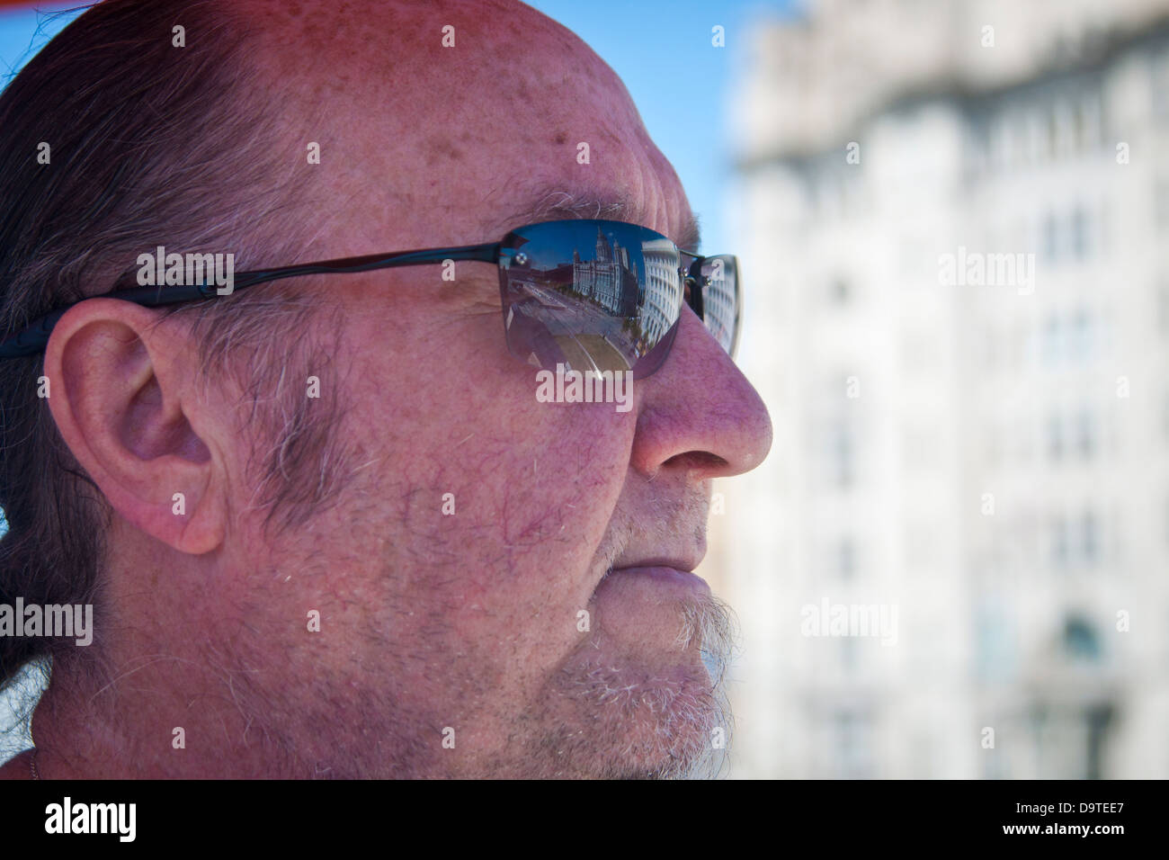 Ein Scouser Greis mit der Leber Gebäude spiegelt sich in seine Sonnenbrille sitzt außen denken während einer Hitzewelle in Großbritannien Stockfoto