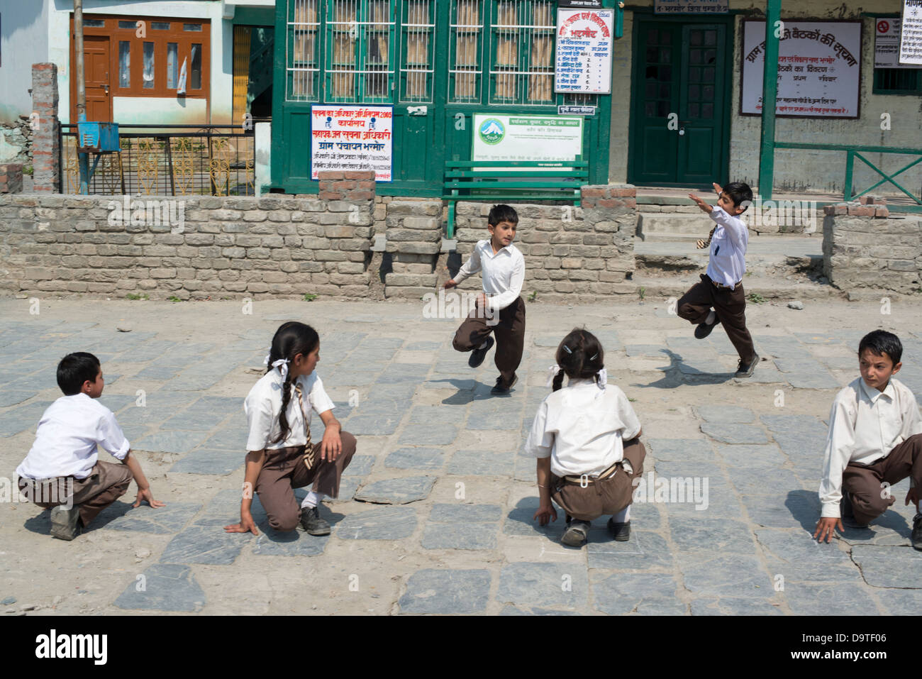 Indische Grundschulkinder spielen Sie eine Partie von Kho Kho auf dem Dorfplatz in Bharmour, Himachal Pradesh, Indien Stockfoto
