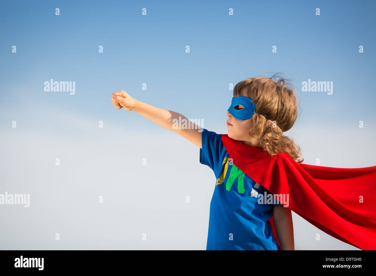 Superheld Kind vor blauem Himmelshintergrund. Mädchen-Power-Konzept Stockfoto