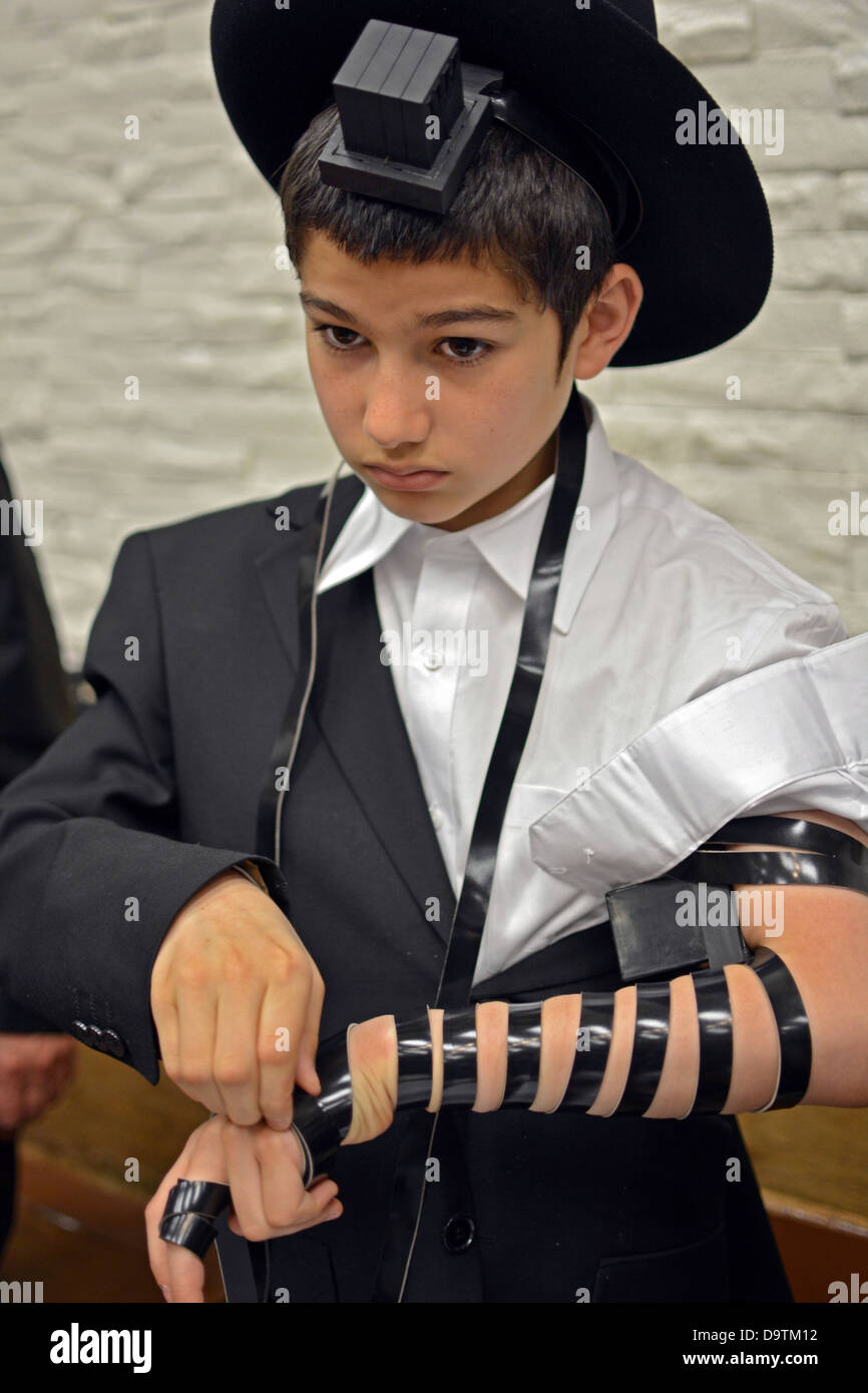 Religiöse jüdische junge setzt auf Gebetsriemen - Drang - zum ersten Mal in der Lubawitscher Synagoge in Brooklyn, New York Stockfoto