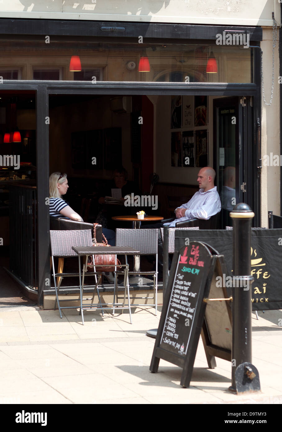 Ein junges Paar sitzen in einem Café-Fenster auf eine Hauptstraße Stockfoto