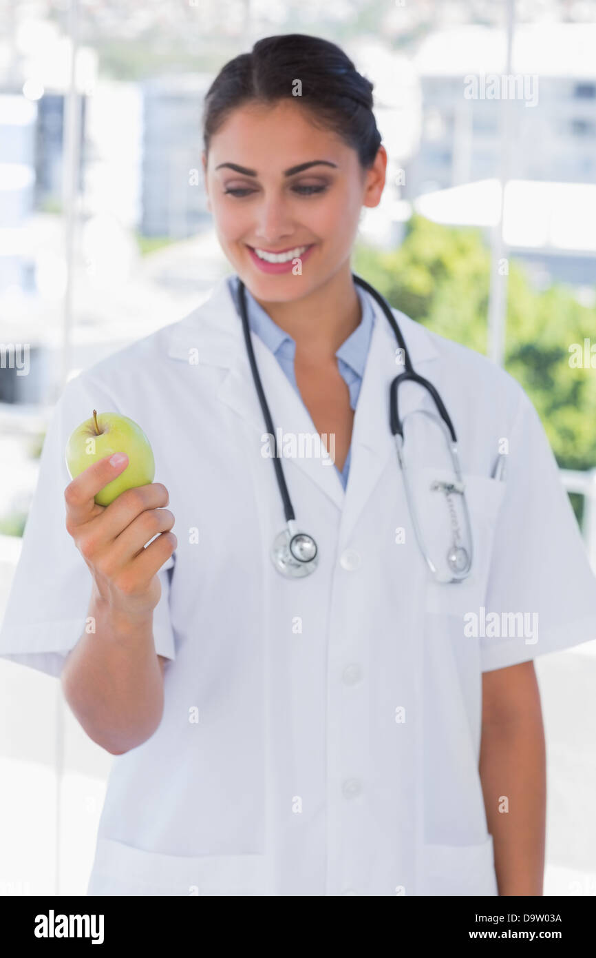 Glückliche junge Ärztin hält einen grünen Apfel Stockfoto