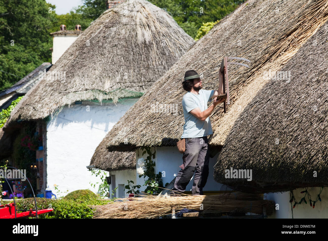 Ein Mann, ein Strohdach auf ein Haus zu reparieren; Adare Grafschaft Limerick Irland Stockfoto