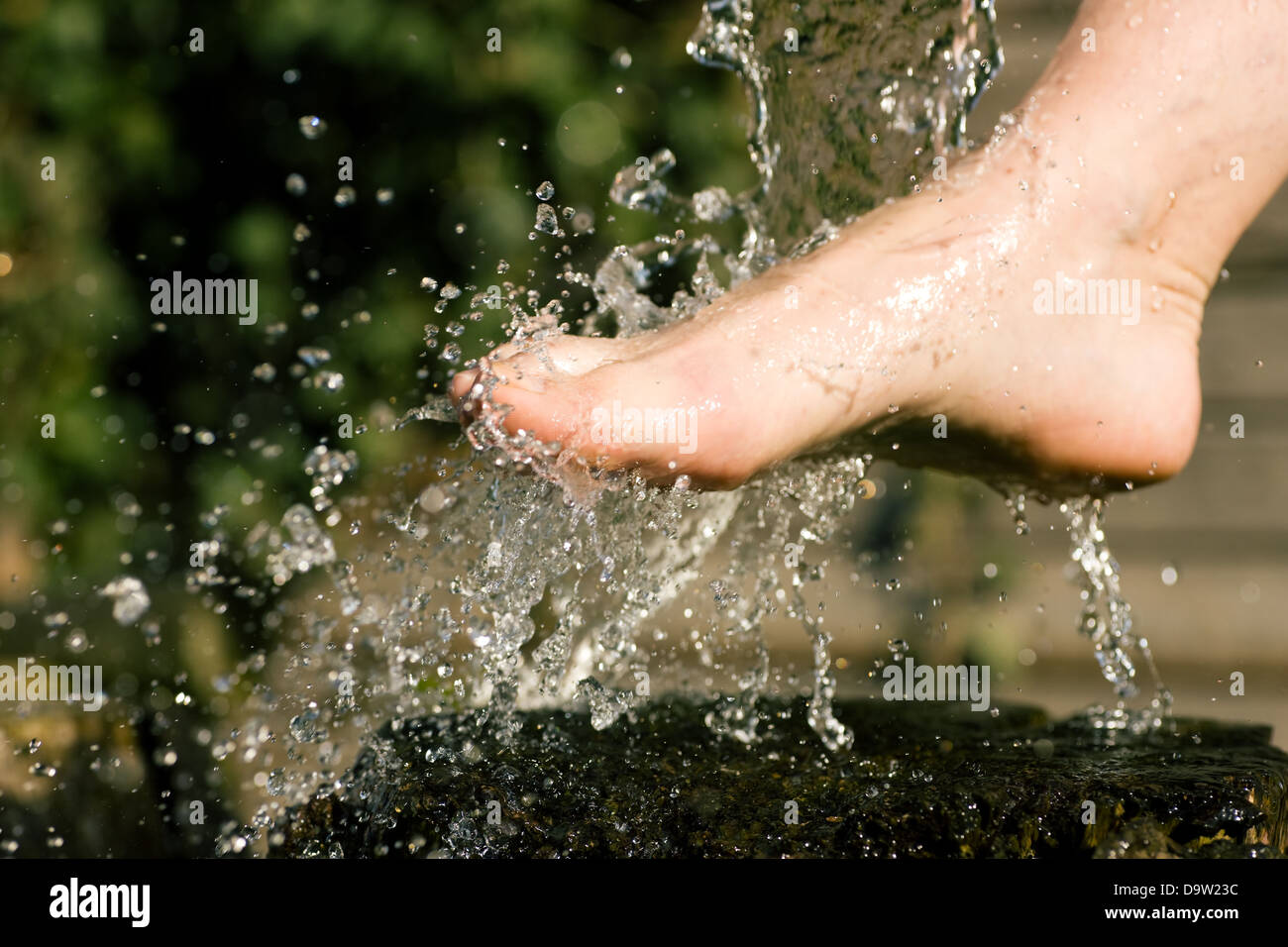 Spritzen mit kaltem Wasser geduscht auf Füßen in einer alternativen Therapie-Sitzung; Tropfen eingefroren Stockfoto
