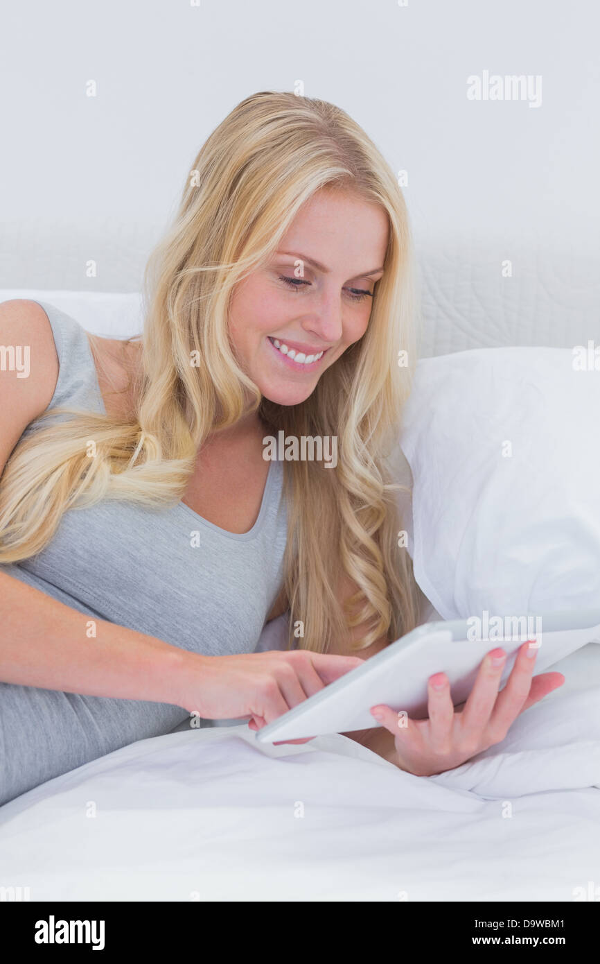 Fröhliche Frau, die ihr Tablet im Bett zu berühren Stockfoto