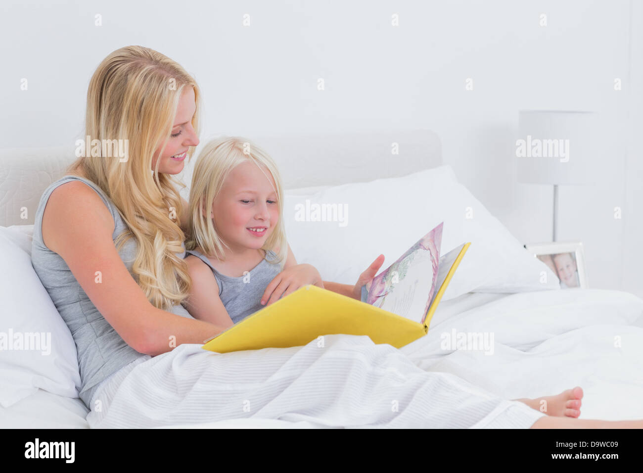 Blonde Mutter zu ihrer Tochter eine Geschichte vorlesen Stockfoto