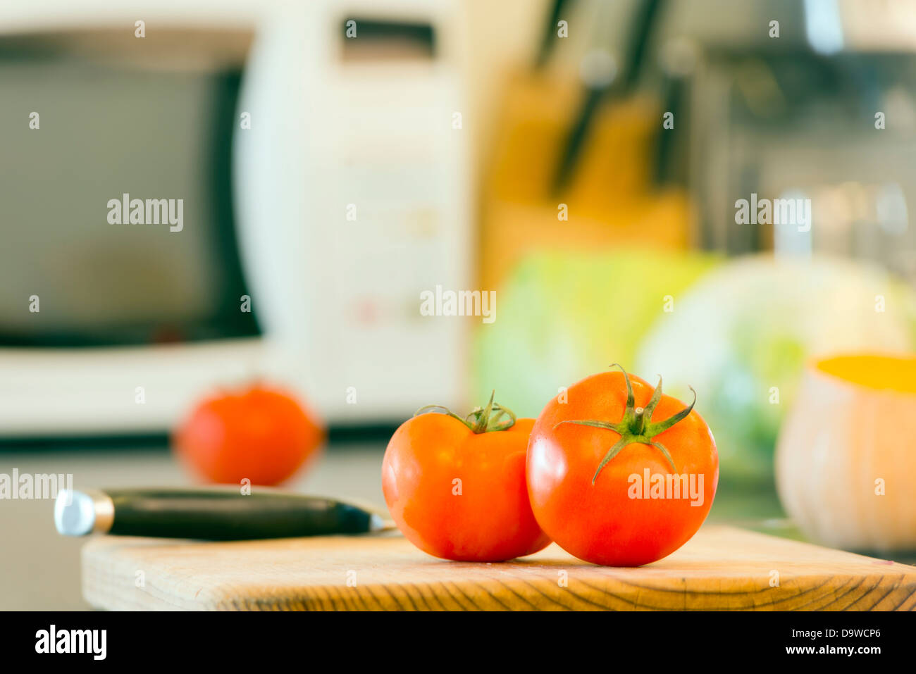Zubereitung von frischen Speisen auf der Küchenbank, mit Tomaten, Kürbis und andere Gemüse im Hintergrund Stockfoto