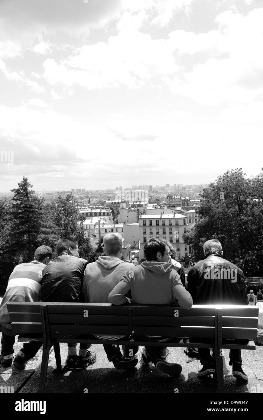 Eine Gruppe von männlichen Jugendlichen sitzen auf einer Bank mit Blick auf Paris von Sacre-Coeur vor ihnen. Stockfoto