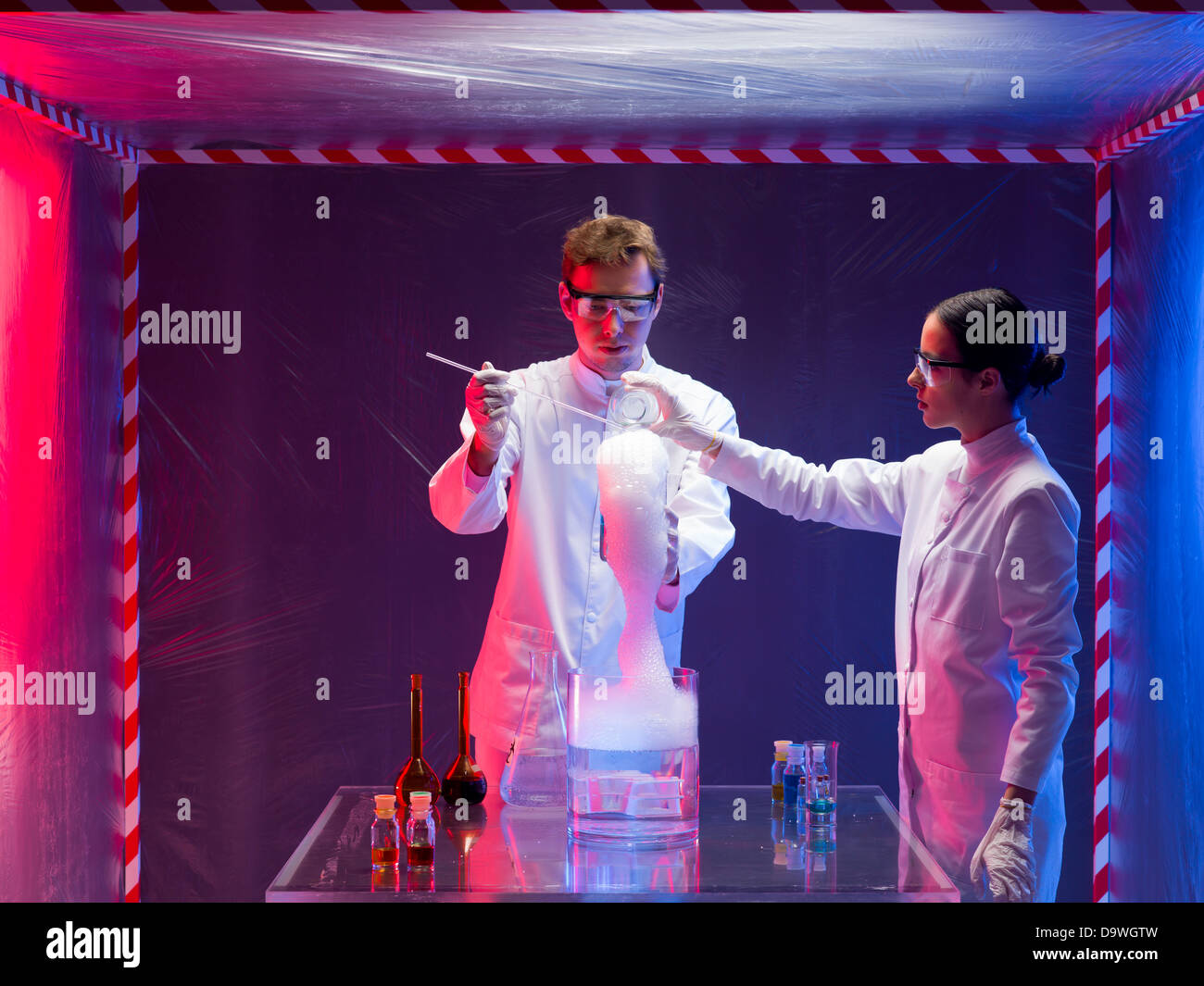 Foto von einem männlichen und weiblichen Wissenschaftler innen ein Biohazard schützenden Raum testen die toxischen Chemikalien während der Rauch comin Stockfoto