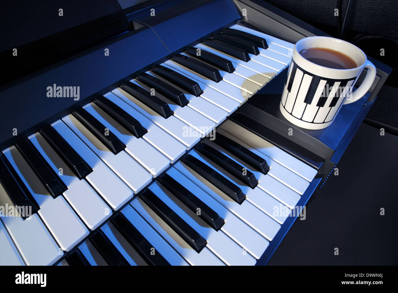 Zwei manuelle elektrische Tastatur und eine Tasse Tee (Milch, ohne Zucker). Stockfoto