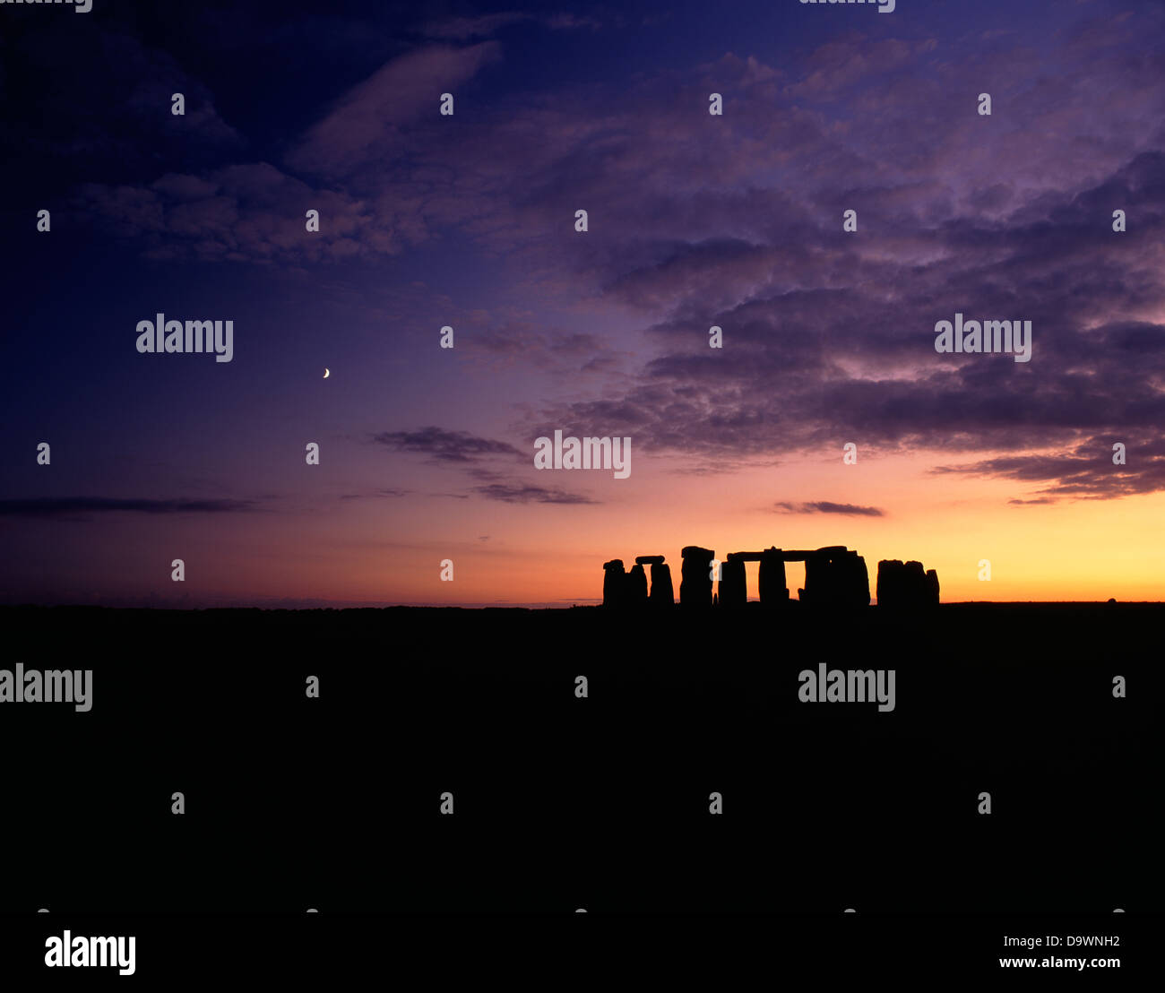 Eine weite Landschaft Blick auf die Stonehenge Trilithons Silhouette nach Sonnenuntergang und Mondaufgang. Wiltshire, England Stockfoto