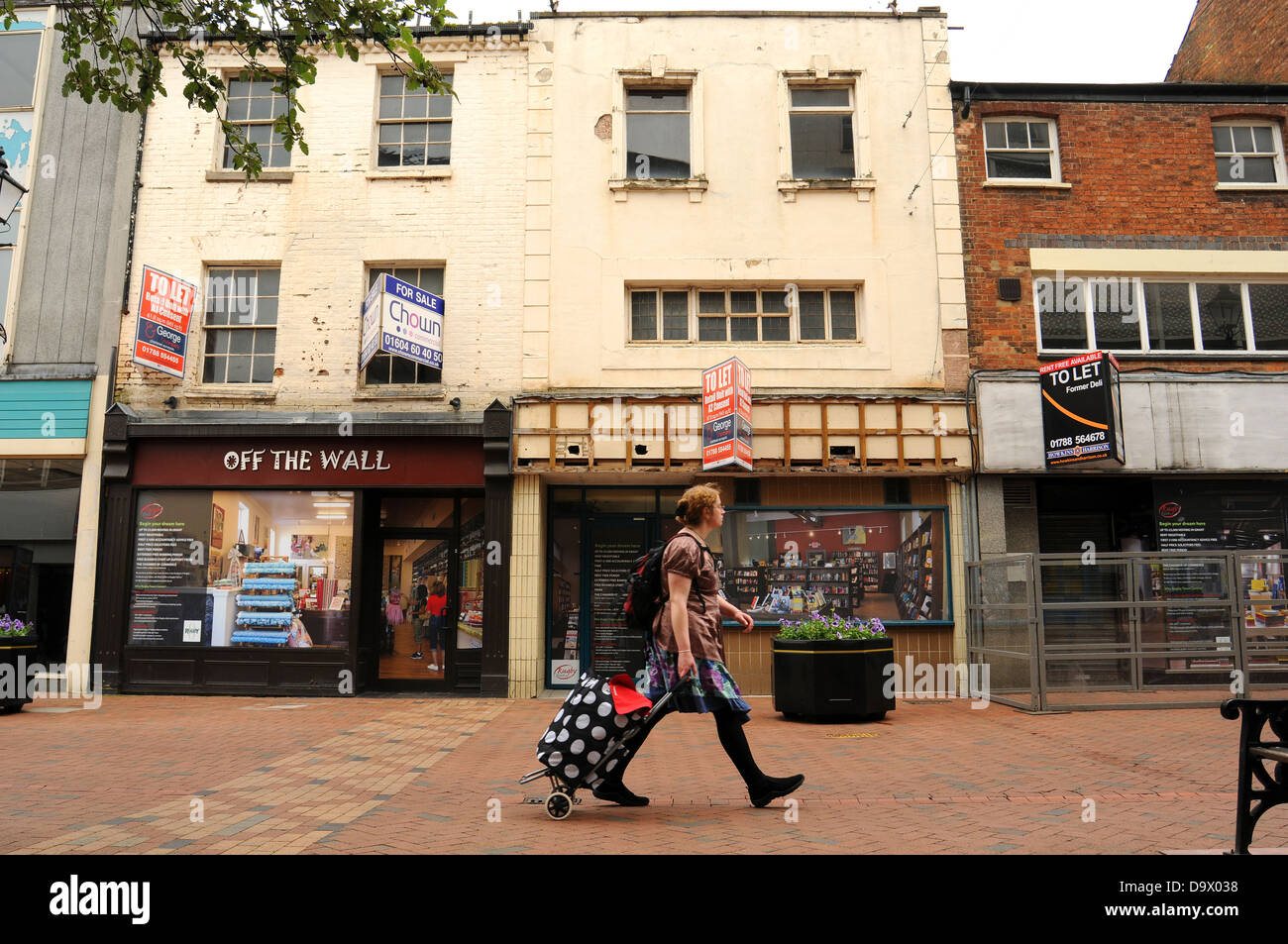 Eine Shopper geht vorbei an leerstehenden Läden in High Street, Rugby, Warwickshire. Stockfoto