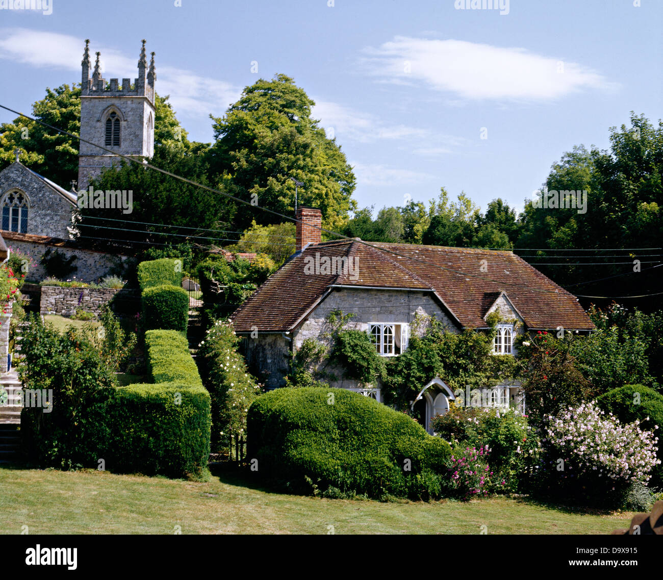 Beschnittene Hecken im Garten des alten Land Pfarrhaus vor der Kirche auf kleine Hügel im englischen Dorf Stockfoto