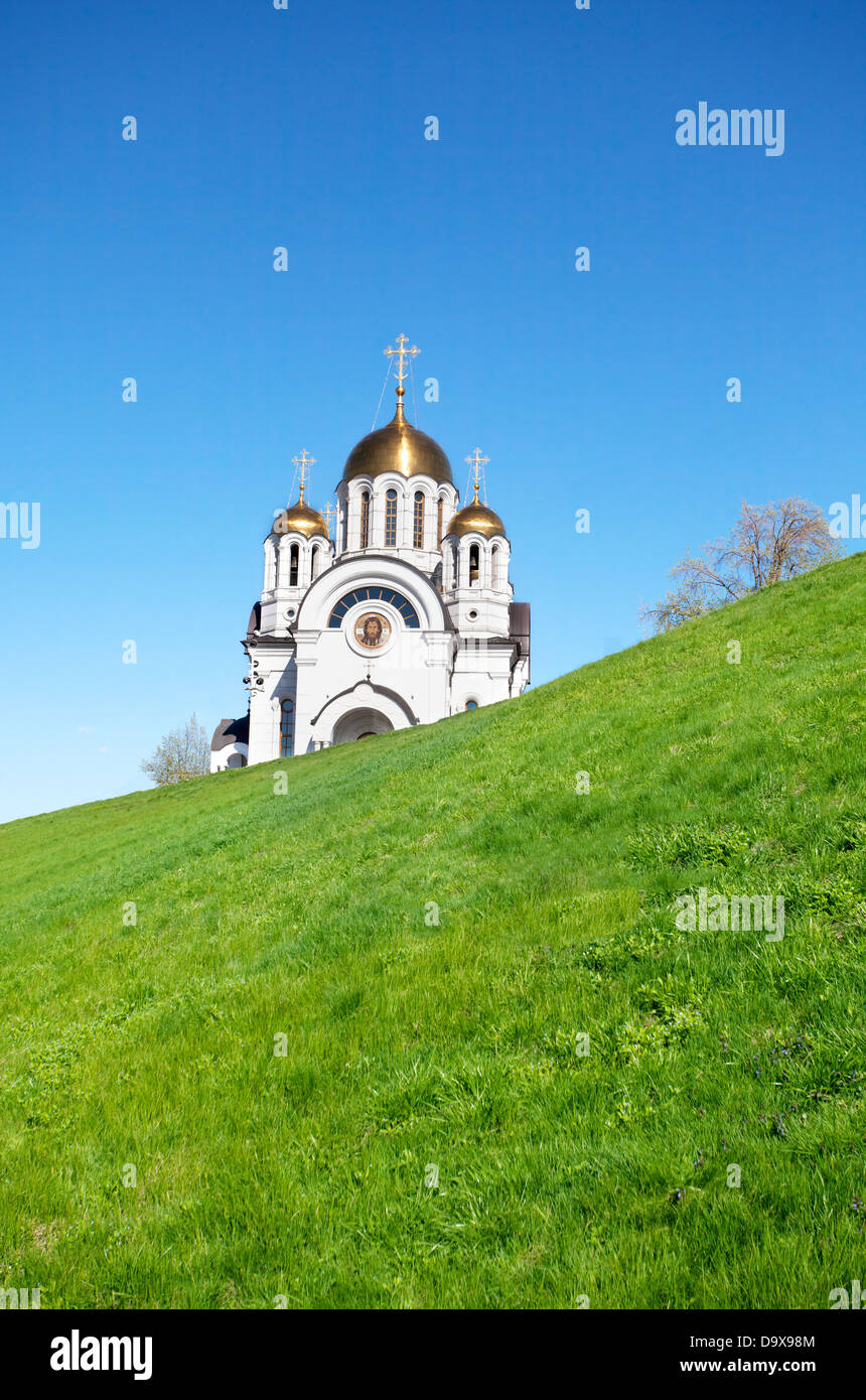 Weißen orthodoxen Kirche mit golden glänzenden Kuppeln auf grünem Hügel über blauen Himmel Stockfoto