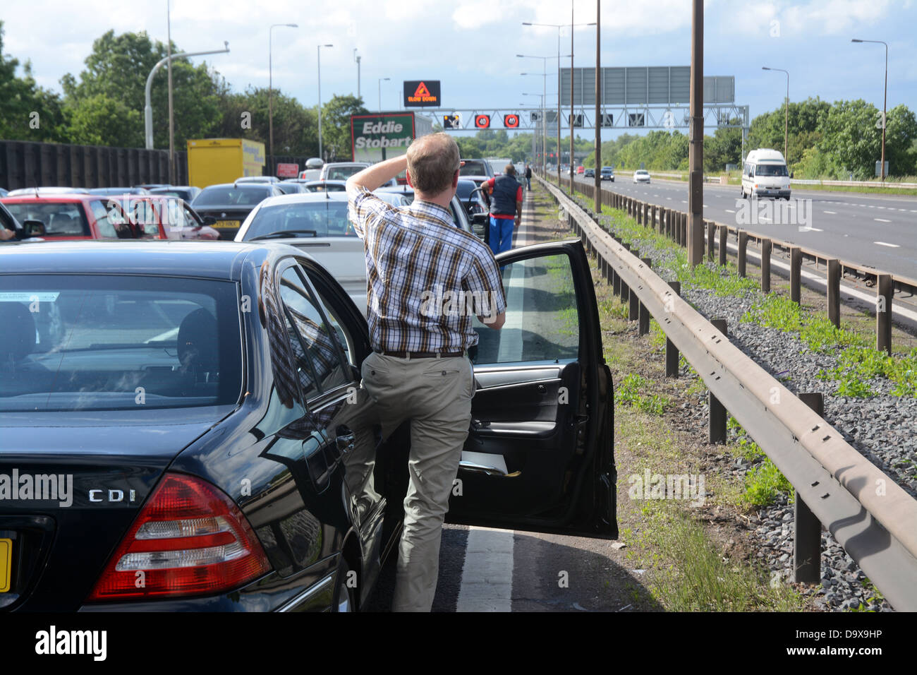 Ein Mann steigt aus seinem Auto in einen Stau auf der Autobahn m6 in der Nähe von Birmingham Stockfoto