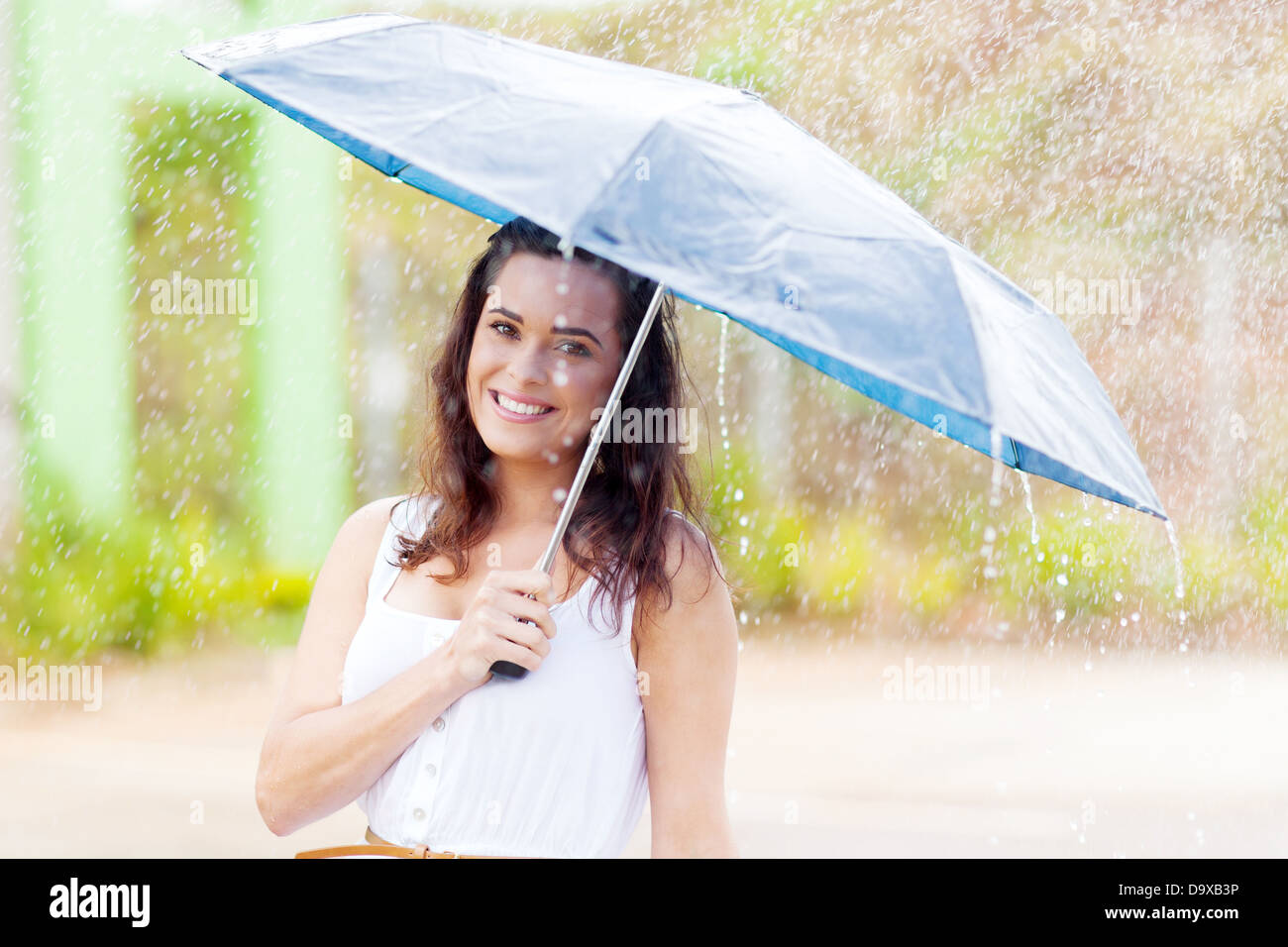 hübsche junge Frau im Regen mit Regenschirm Stockfoto